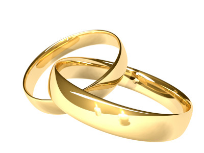 Two linked gold rings.  Two candles reflected in the gold.  Shallow depth of field.